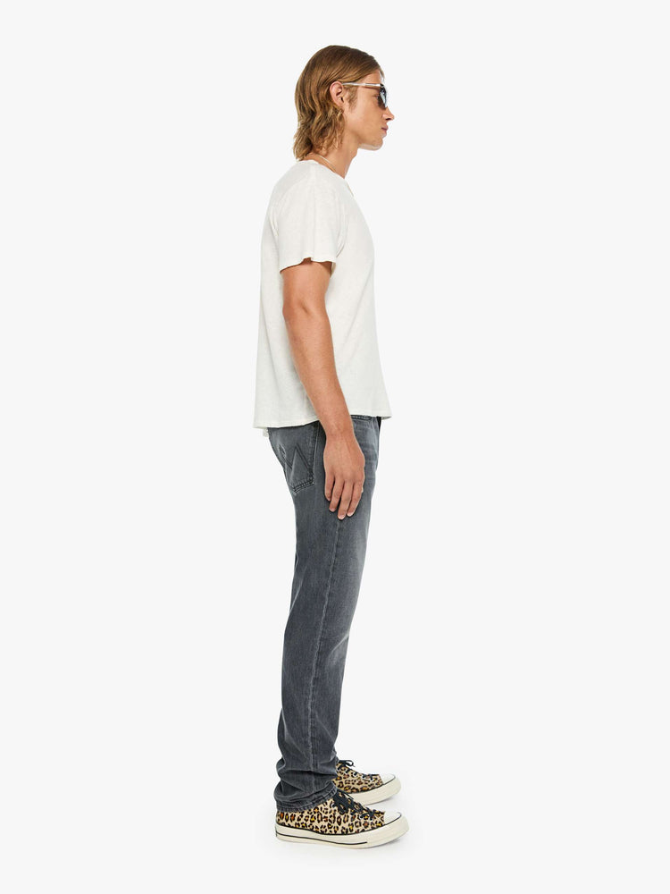 Side view of a man in a dark grey standard straight leg with a mid rise, button fly and 32-inch inseam with a clean hem.