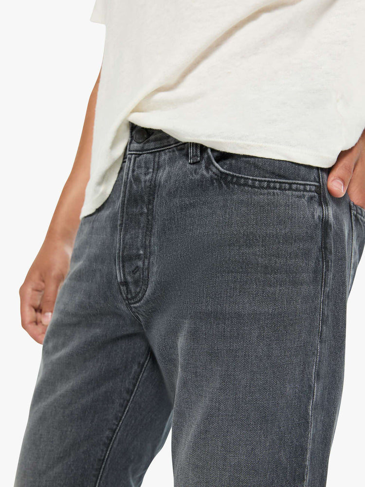 Close up view of a man in a dark grey standard straight leg with a mid rise, button fly and 32-inch inseam with a clean hem.