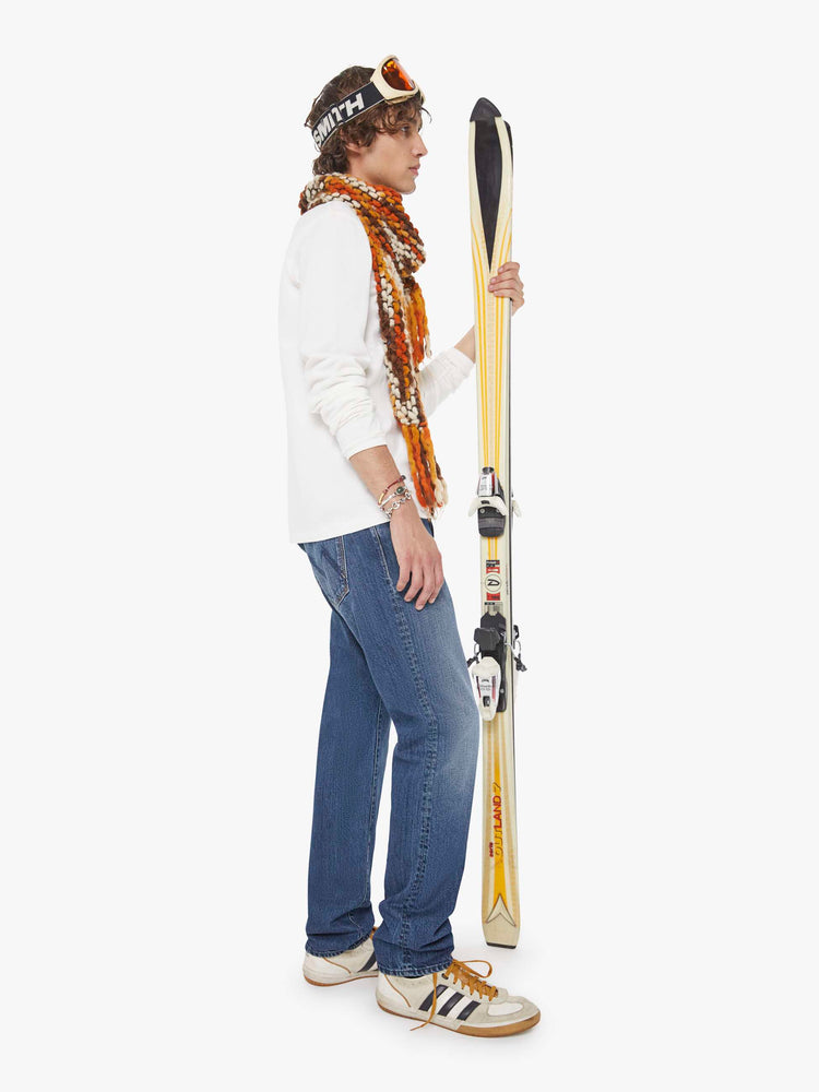 Side view of a man in a mid blue standard straight leg with a mid rise, button fly and 32-inch inseam with a clean hem.