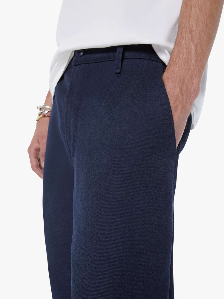 Close up view of a man in a navy classic pant with slit pockets, a zip fly and loose leg.