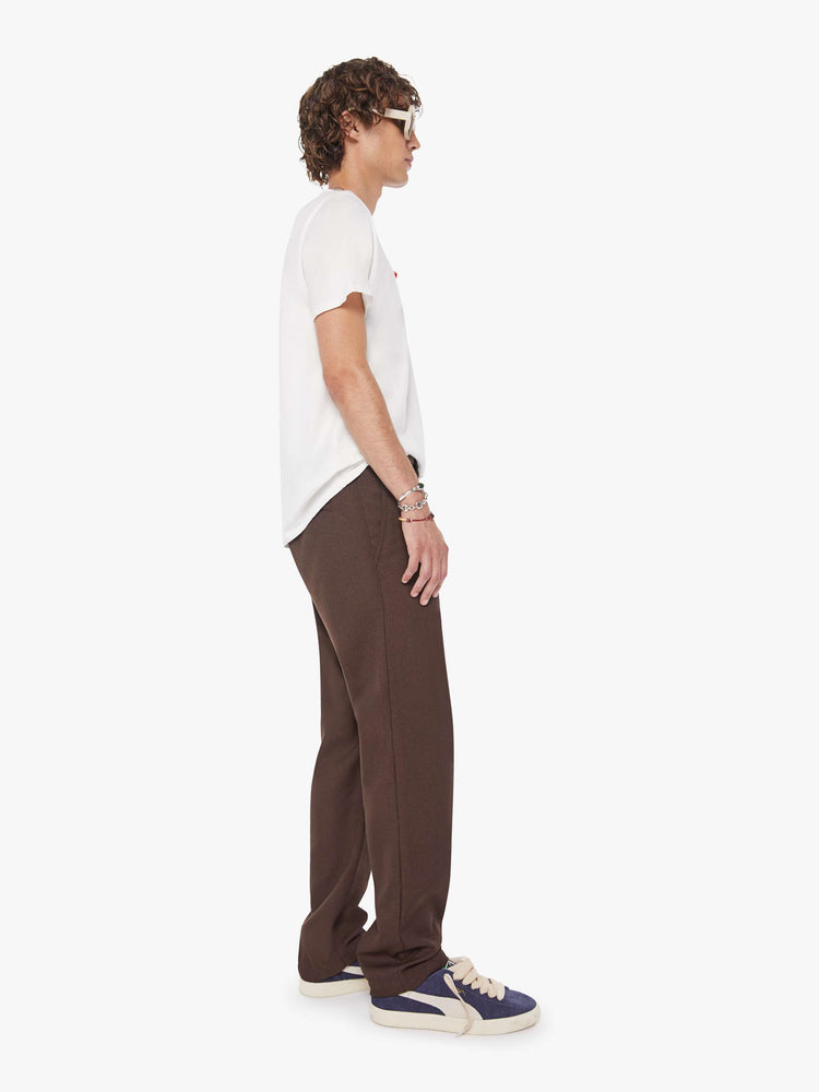 Side view of a man in a dark brown  classic pant with slit pockets, a zip fly and loose leg. 