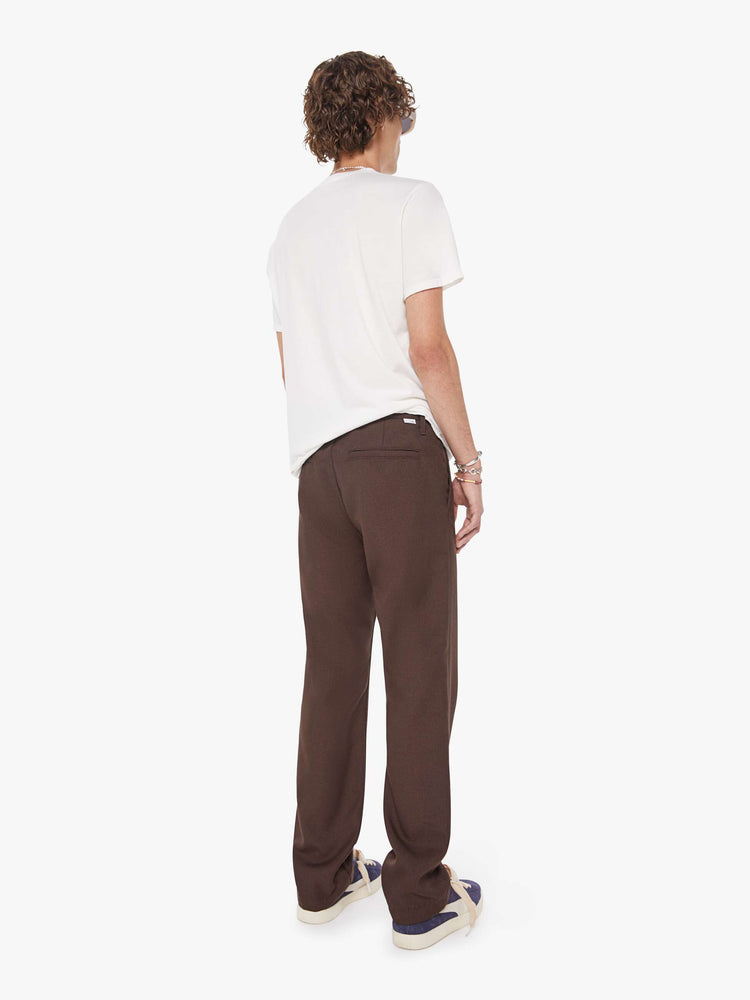 Back view of a man in a dark brown  classic pant with slit pockets, a zip fly and loose leg. 