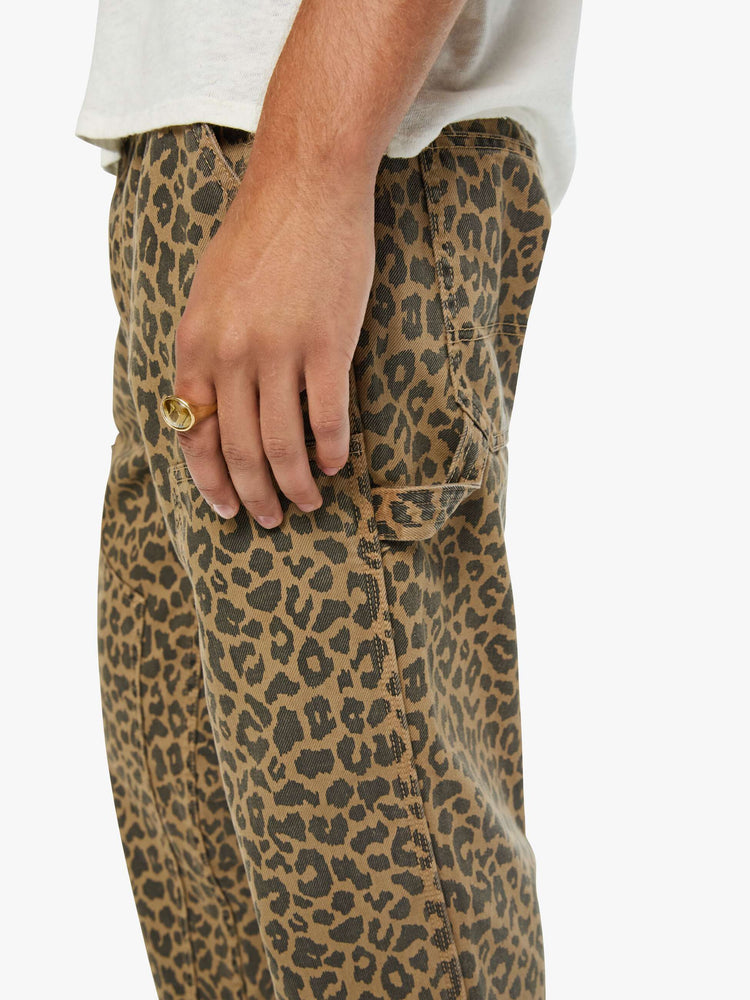 Close up view of a man in a leopard print classic pant with patch pockets, a zip fly, hammer loop and loose leg.