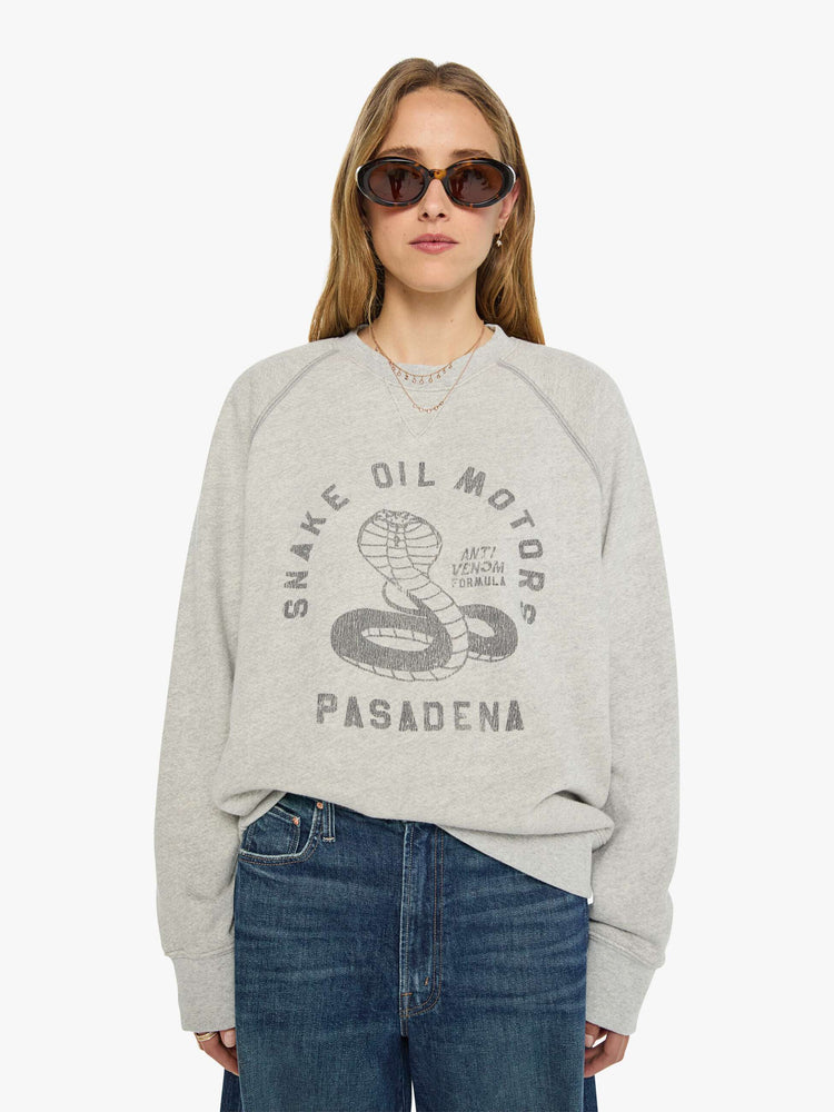 WOMAN front view heathered light grey sweatshirt features a faded snake graphic and block text on the front.