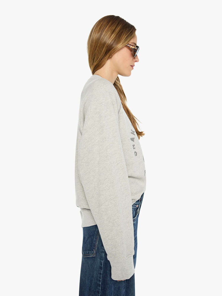 WOMAN side view heathered light grey sweatshirt features a faded snake graphic and block text on the front.