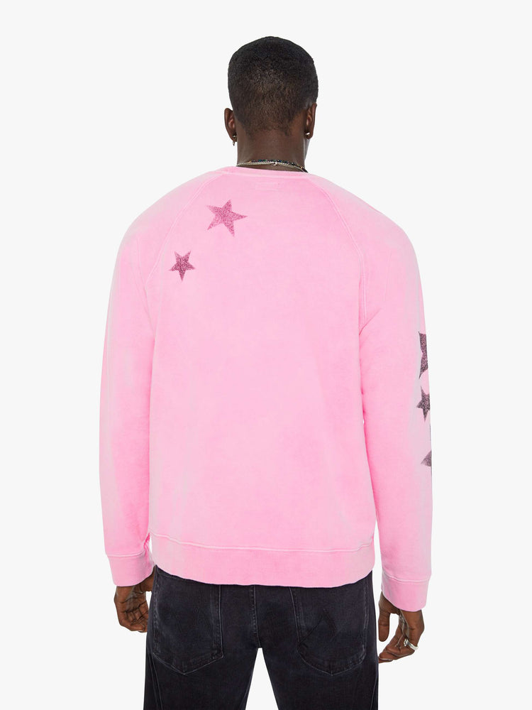Back view of a man in bright pink sweatshirt with black stars printed across the body and one sleeve.