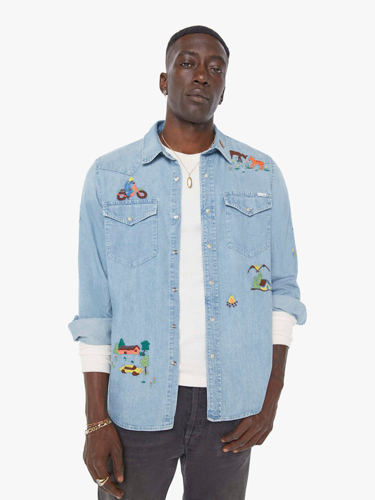 Front view of a man in a light blue denim button up with fading and colorful embroidery throughout.