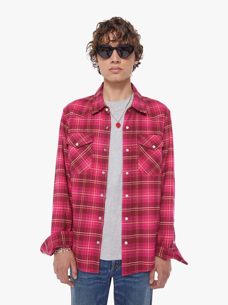Front view of a man in a hot pink and red plaid print classic button down shirt with flap patch pockets, long sleeves and a curved hem.