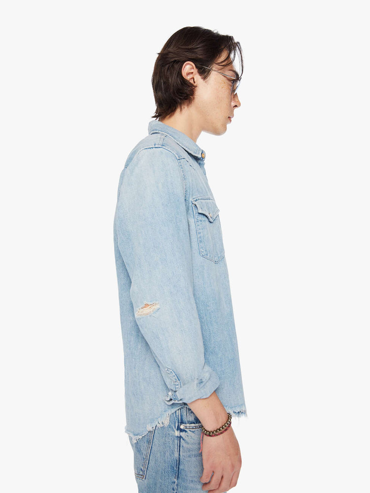 Side view of a men classic Western-inspired shirt with buttons, flap patch pockets, long sleeves and a curved hem in a light blue wash.