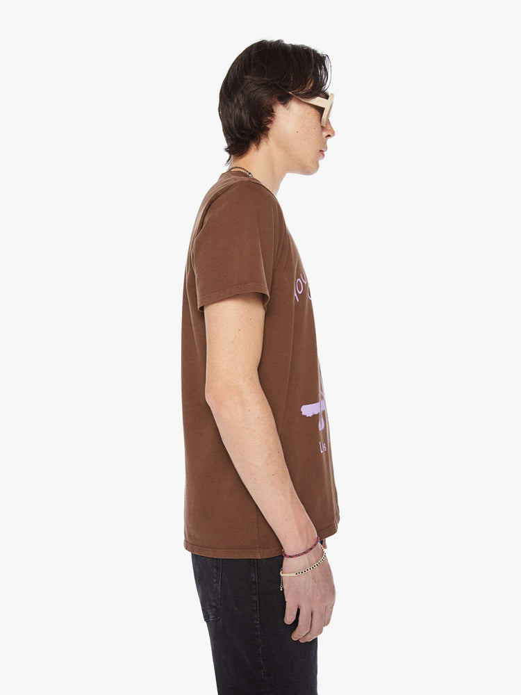 Side view of a men classic crewneck tee with short sleeves in brown with lavender roadrunner graphic.