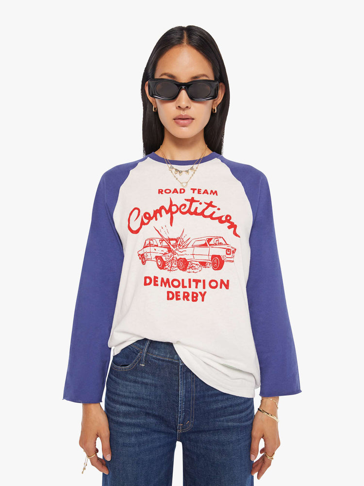 WOMAN front view in a  baseball tee with a crew neck, 3/4-length frayed sleeves and a curved hem in white with blue sleeves and a red demolition derby graphic on the front.