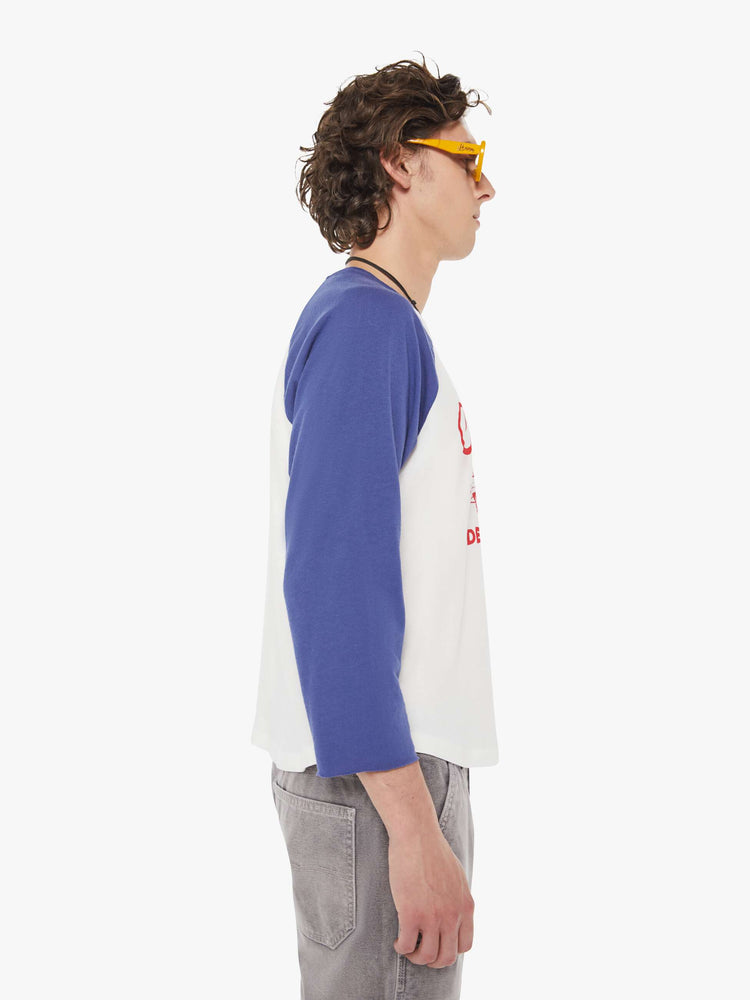MEN side view in a  baseball tee with a crew neck, 3/4-length frayed sleeves and a curved hem in white with blue sleeves and a red demolition derby graphic on the front.