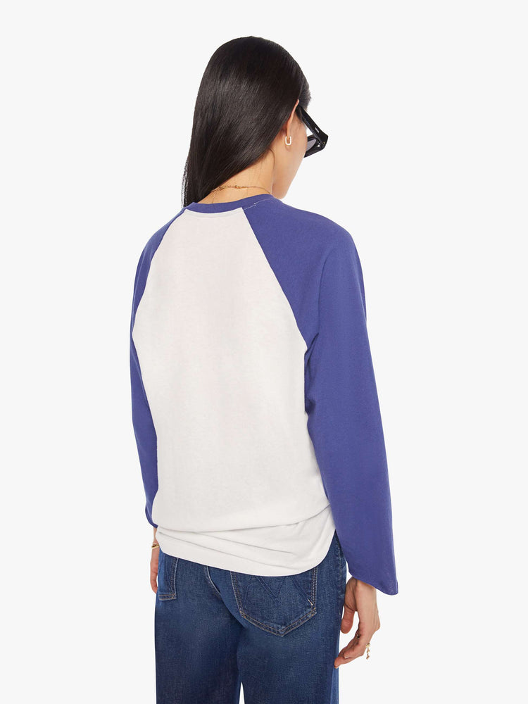 WOMAN back view in a  baseball tee with a crew neck, 3/4-length frayed sleeves and a curved hem in white with blue sleeves and a red demolition derby graphic on the front.