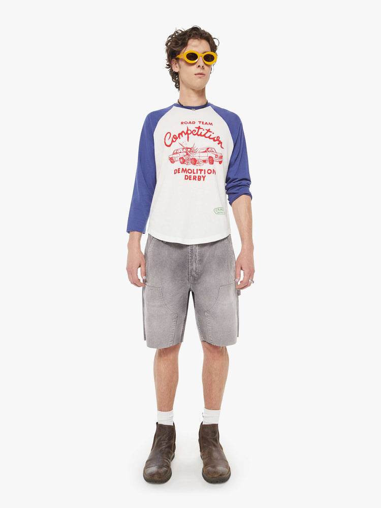 MEN full body view in a  baseball tee with a crew neck, 3/4-length frayed sleeves and a curved hem in white with blue sleeves and a red demolition derby graphic on the front.