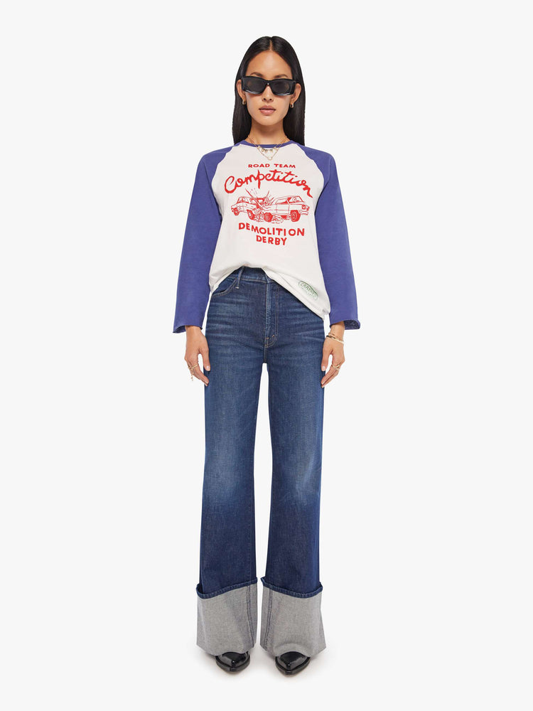 WOMAN full body view in a  baseball tee with a crew neck, 3/4-length frayed sleeves and a curved hem in white with blue sleeves and a red demolition derby graphic on the front.
