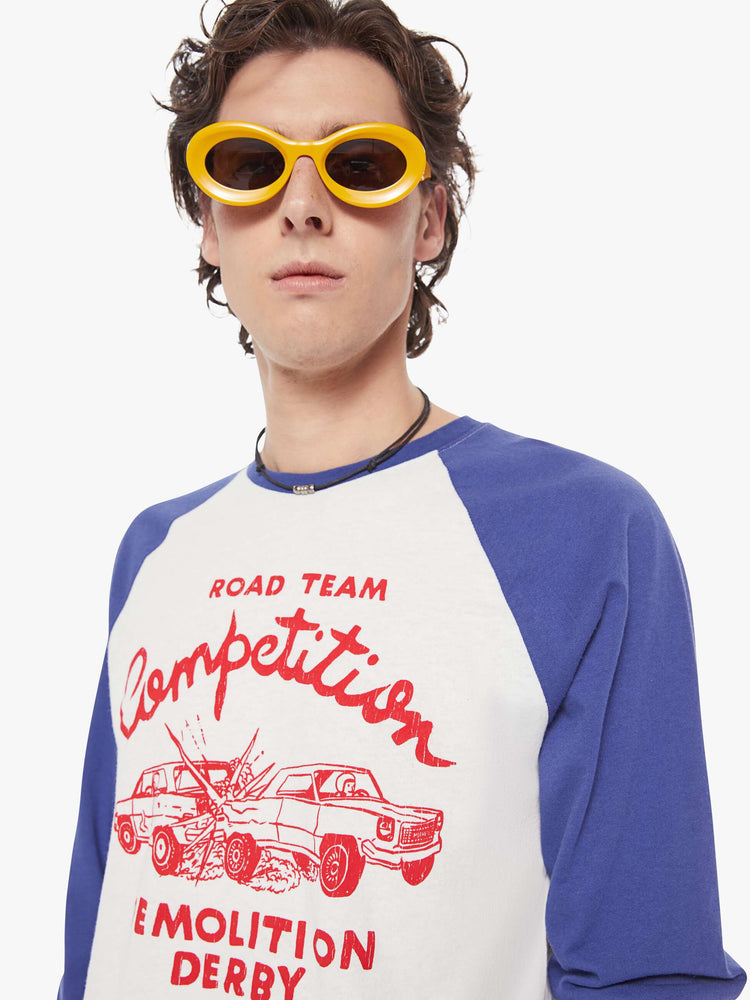MEN close up view in a  baseball tee with a crew neck, 3/4-length frayed sleeves and a curved hem in white with blue sleeves and a red demolition derby graphic on the front.