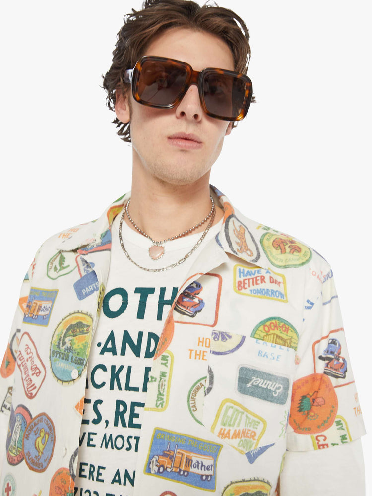 MEN close up view of an off-white with faded patches printed throughout short sleeve button-up with a patch pocket.