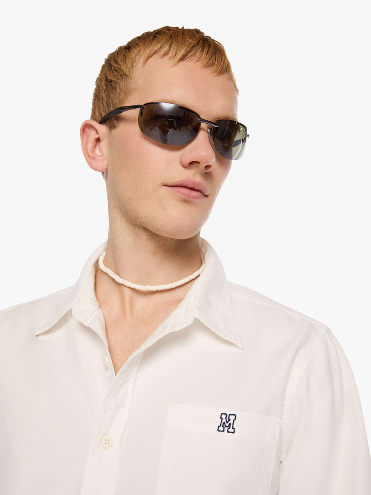 Close up view of  man in the top is designed in white with a navy M embroidered on the chest.
