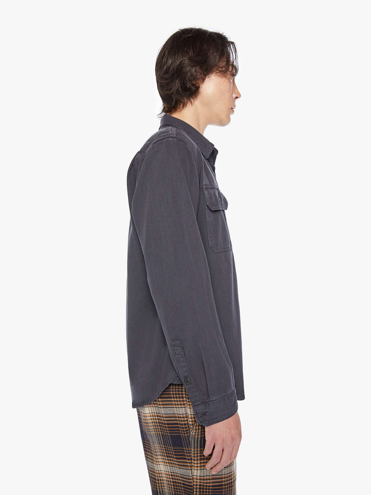 Side view of a mens classic button-up shirt with double patch pockets, long sleeves and a curved hem in a faded black hue.