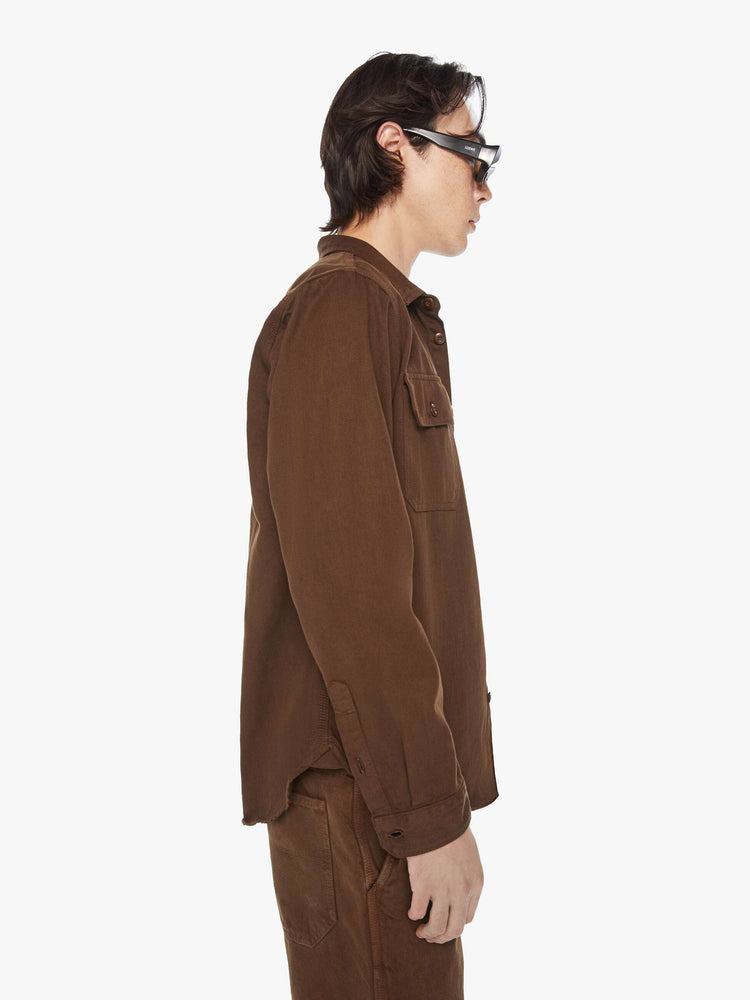 Side view of a men's classic button-up shirt with double patch pockets, long sleeves and a curved hem in a dark brown hue.