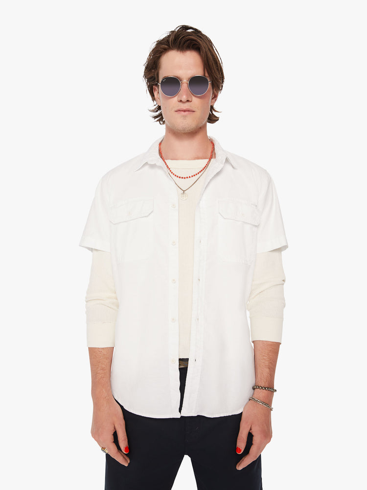 Front view of men short sleeve button-up with patch pockets at the chest and a curved hem in a bright white hue.