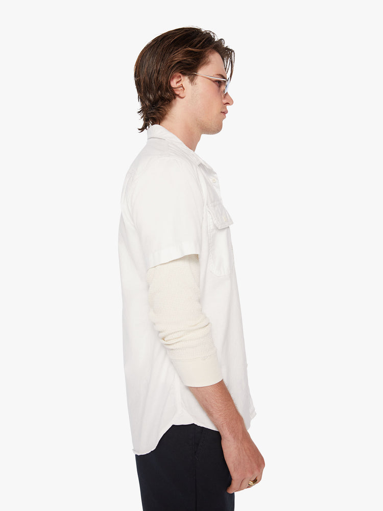 Side view of men short sleeve button-up with patch pockets at the chest and a curved hem in a bright white hue.