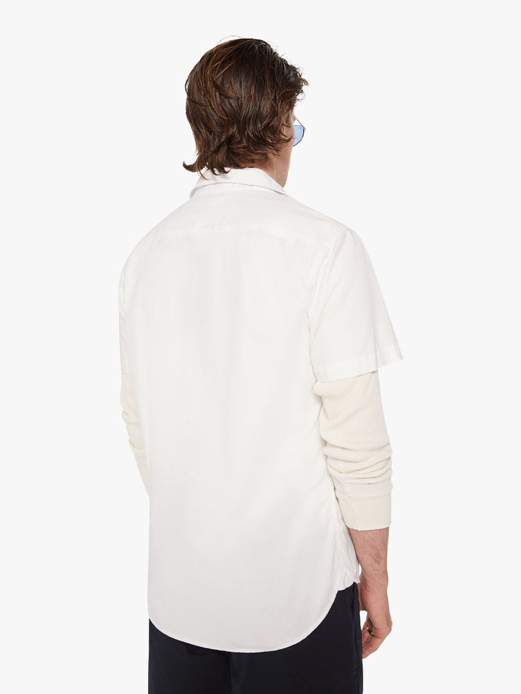 Back view of men short sleeve button-up with patch pockets at the chest and a curved hem in a bright white hue.