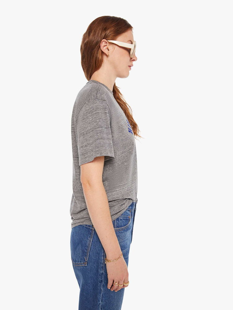 WOMEN side view of a woman in a heather grey unisex crew neck tee featuring a faded blue graphic of hands of the words "HIGHER HOPES".