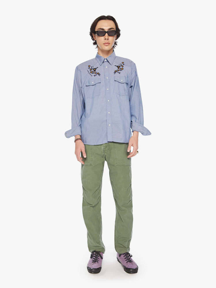 Full body view of a men classic long sleeve button-up with Western-inspired patch pockets in a light blue hue with embroidered bulls, flowers and text on the chest.
