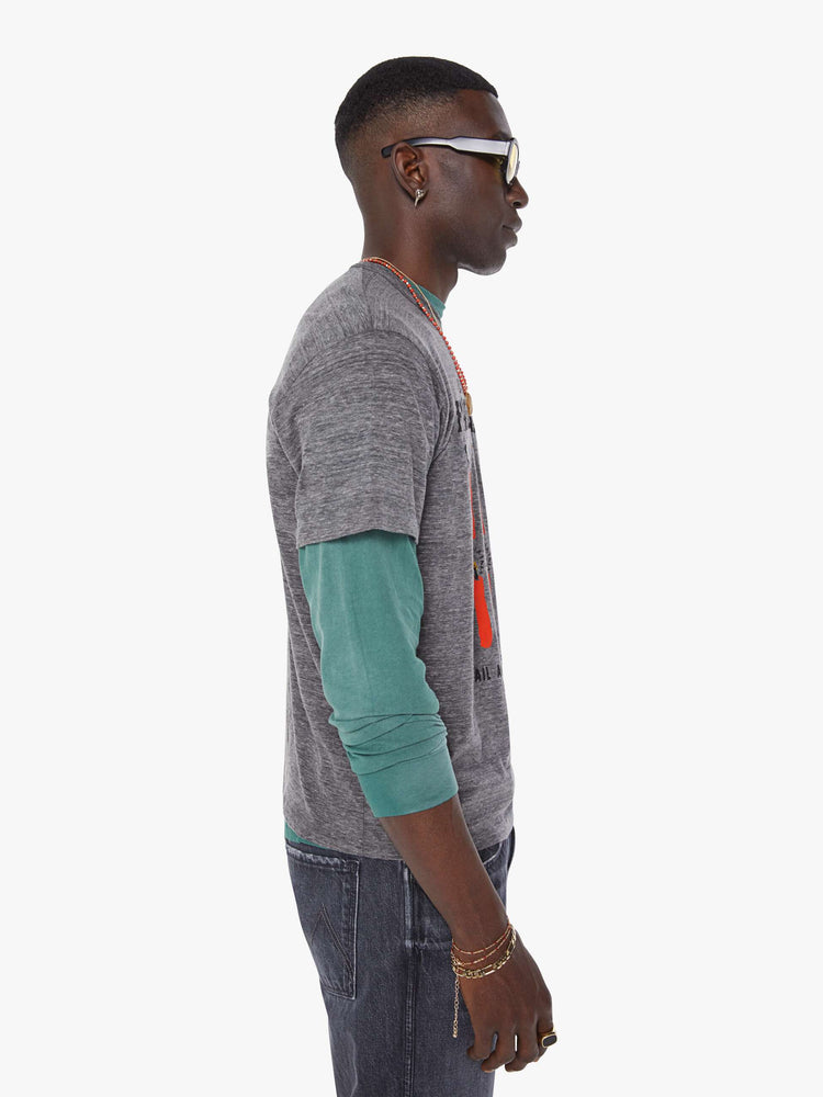 MEN side view in an oversized tee in heathered grey, the tee features a firecracker graphic in red and black on the front.
