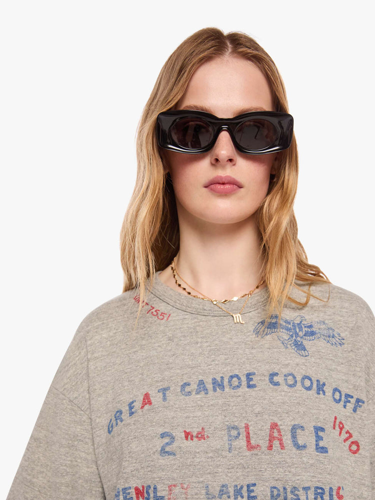 WOMAN close up view in heathered grey tee with a faded red and blue text graphic on the front inspired by a vintage cookoff.