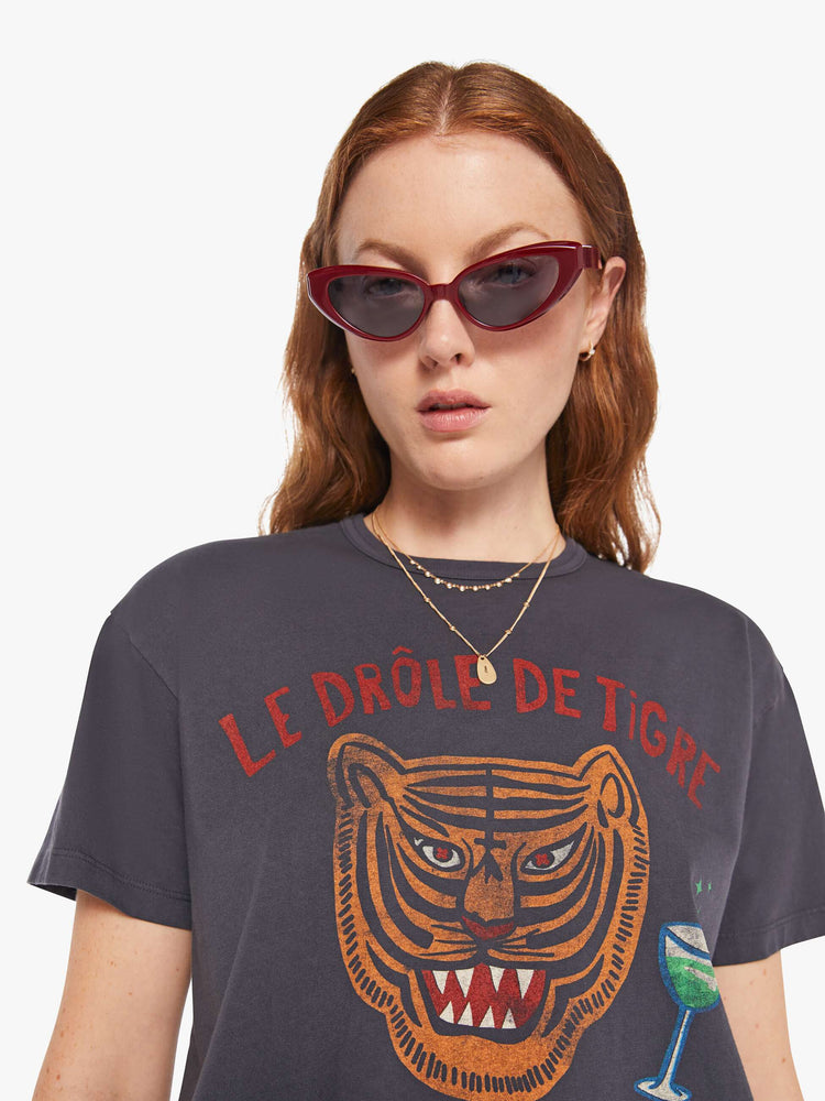 WOMAN close up view of an oversized tee in faded black with a tiger graphic with text in red and blue on front.