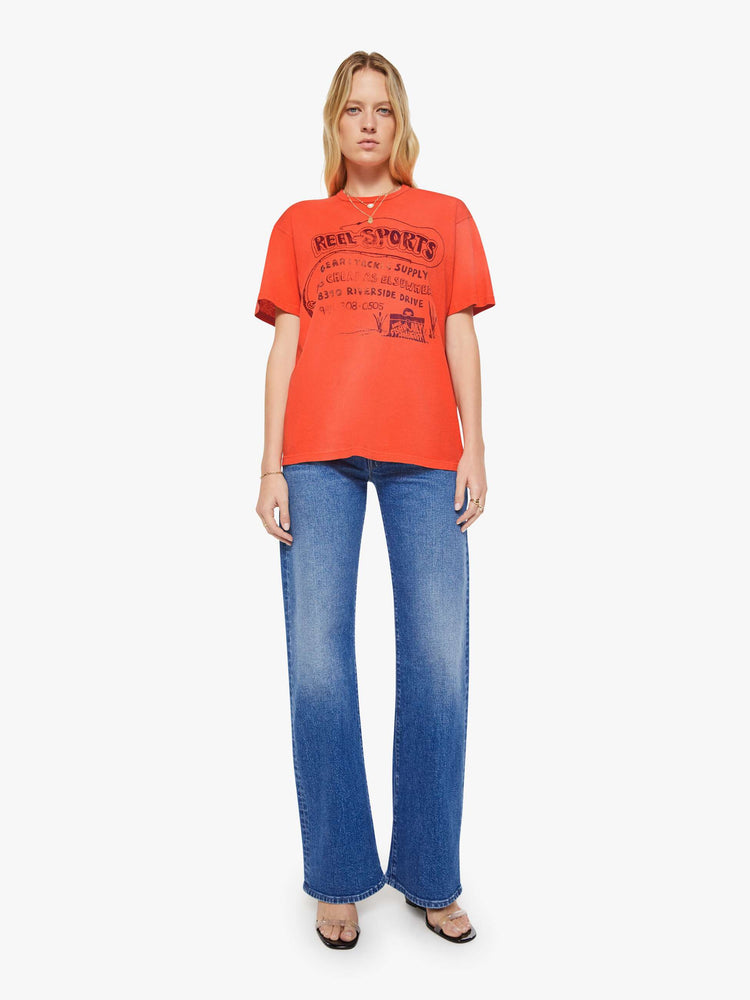 WOMAN front full body view in a red with fading throughout oversized tee features a faded graphic inspired by a vintage sporting goods store on the front.
