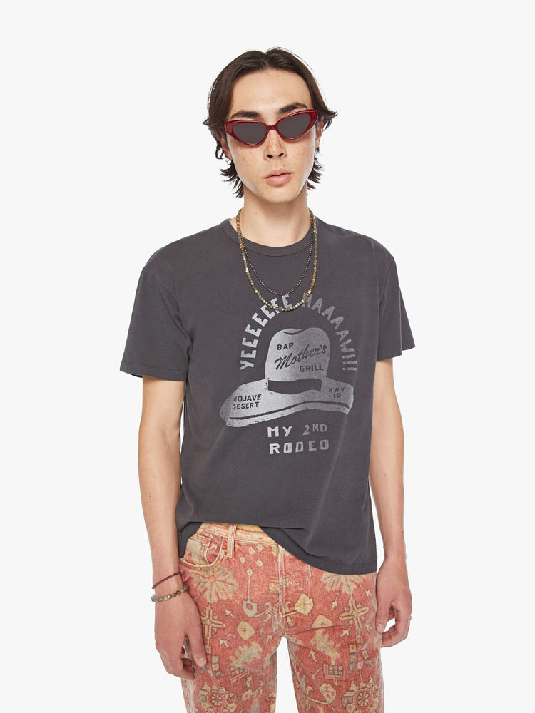 Front view of a men oversized tee with drop shoulders and a loose fit in a faded black tee with a faded sun hat graphic and text.