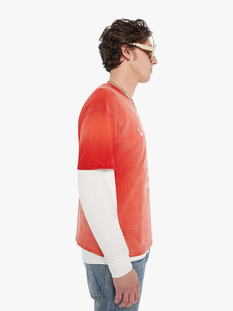 MEN side view in an oversized tee in a red wash with an off-white graphic inspired by an old-school hotel logo.