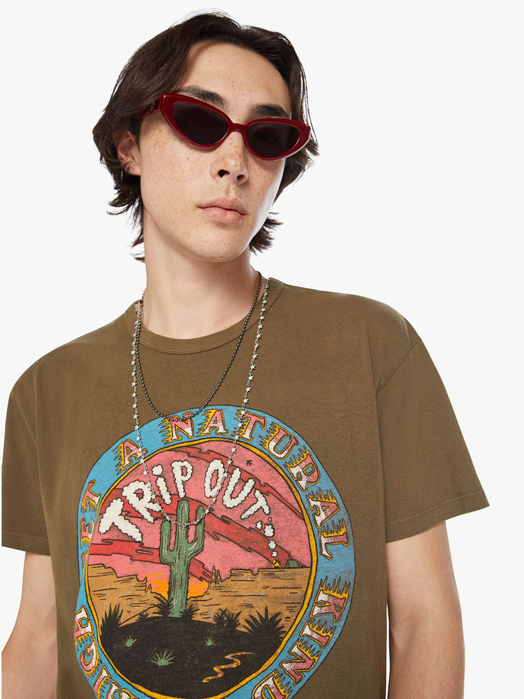 Close up view of a men olive-brown hue oversized tee with drop shoulders and a loose fit with a desert themed graphic.