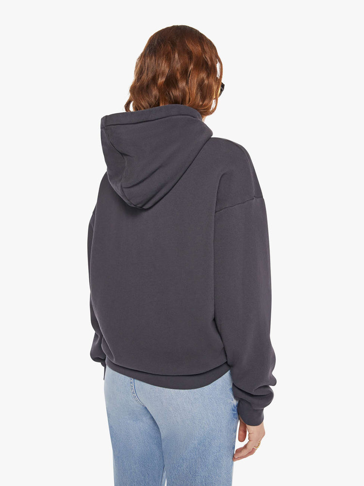 WOMAN back view of an oversized hoodie with drop shoulders, ribbed hems and a front patch pocket in faded black, the hoodie features MOTHER's name in light yellow on the front.