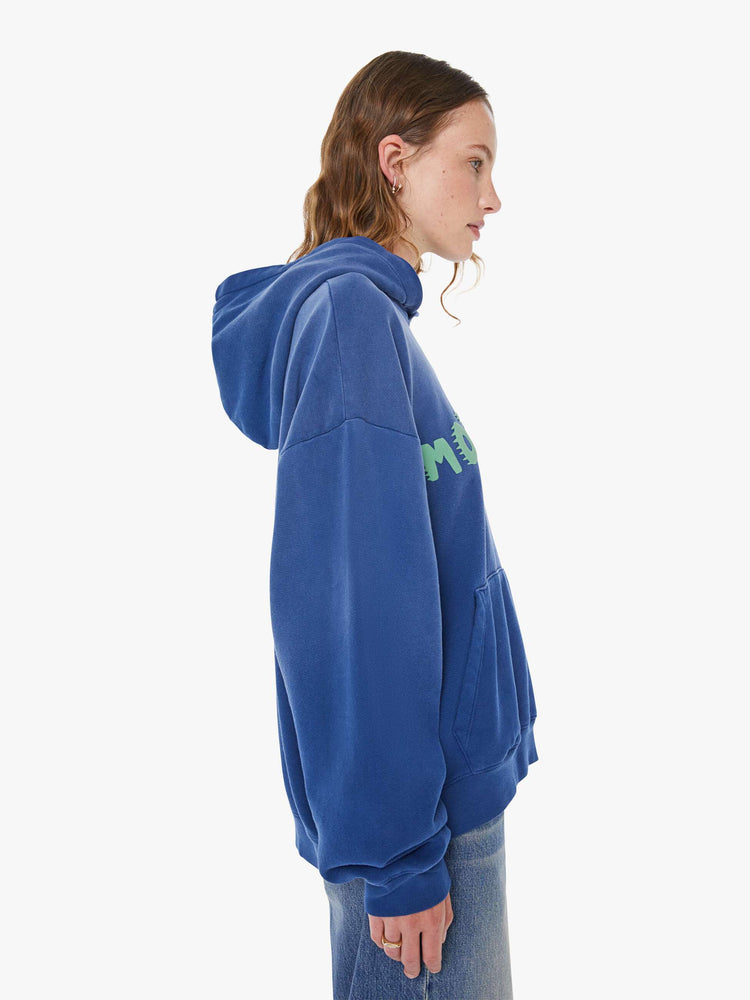 WOMAN side view of a blue  oversized hoodie with drop shoulders, ribbed hems and a front patch pocket.