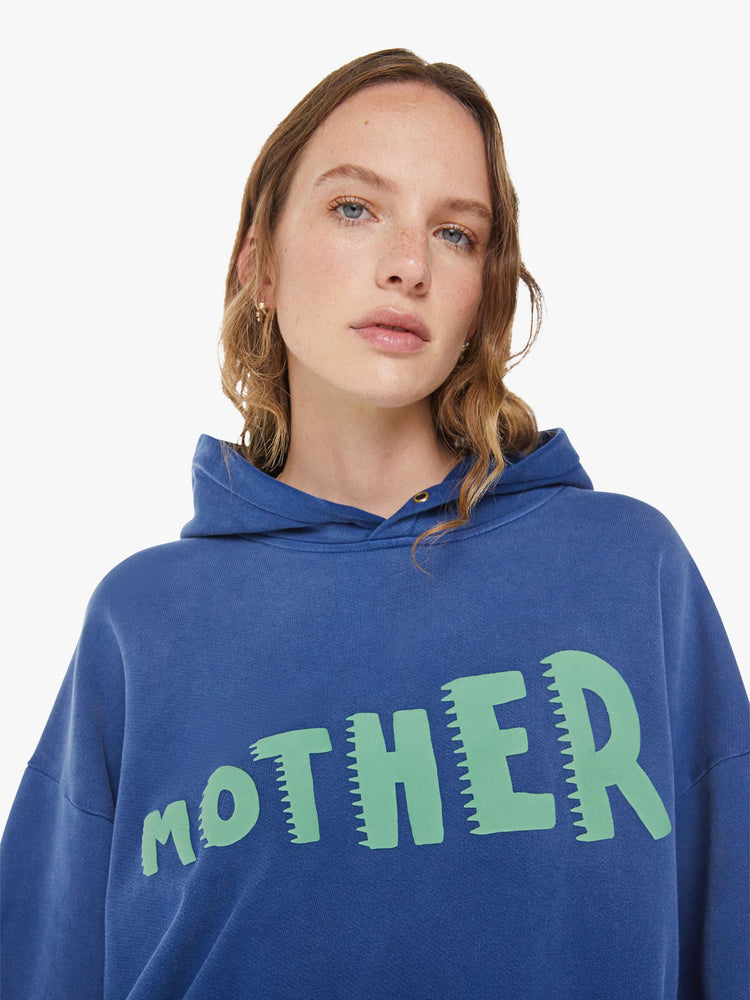 WOMAN close up view of a blue  oversized hoodie with drop shoulders, ribbed hems and a front patch pocket.