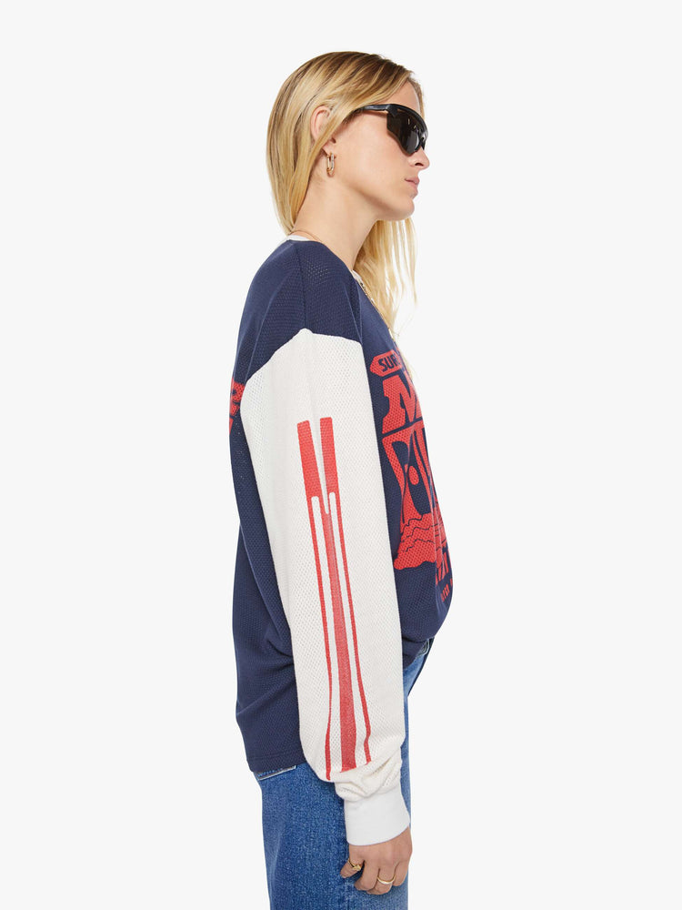 WOMAN side view of a in navy with off-white sleeves, the tee features a text graphic in red on the front oversized long sleeve tee with drop shoulders and a loose fit.