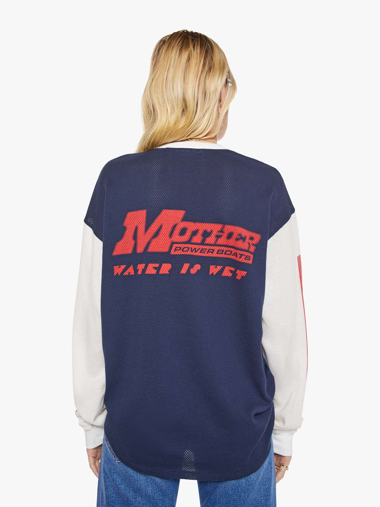 WOMAN back view of a in navy with off-white sleeves, the tee features a text graphic in red on the front oversized long sleeve tee with drop shoulders and a loose fit.