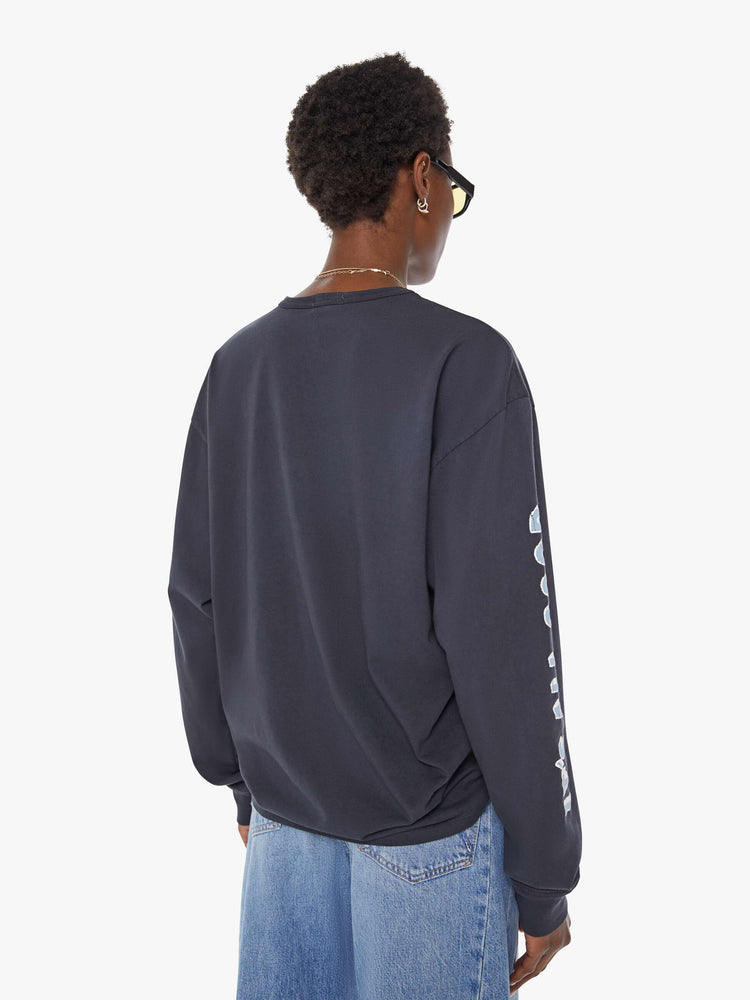 WOMAN back view of a faded black long sleeve tee features a yellow and white text graphic on the front inspired by a vintage mountaineering team shirt.