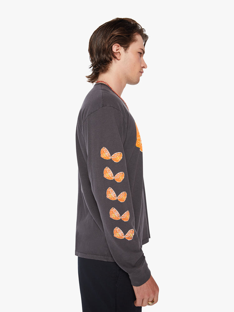 Side view of men oversized long sleeve tee with drop shoulders in a dark grey hue with orange slices down the arm.