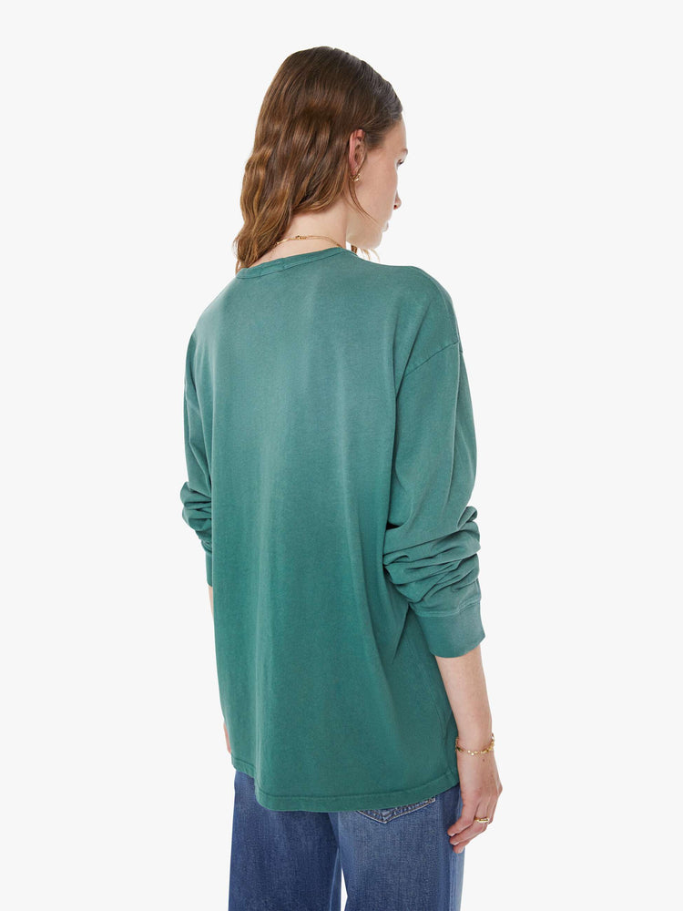 WOMAN back view in a faded turquoise tee with yellow on front oversized long sleeve tee with drop shoulders and a loose fit.