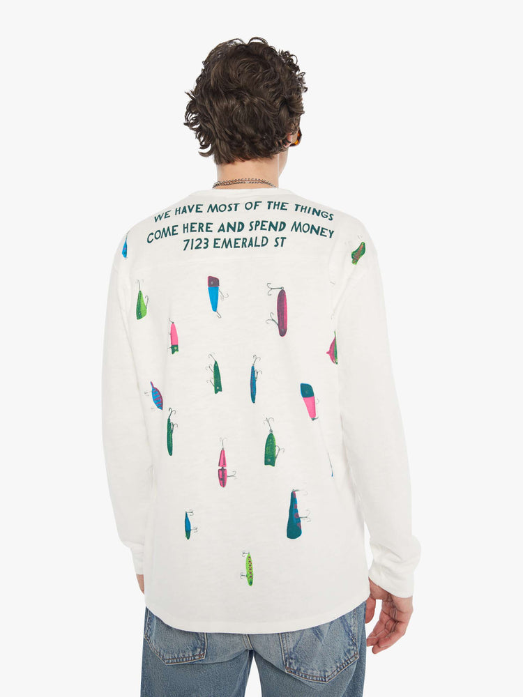 MEN back view of rugby style tee in off white with a green text graphic on the front and colorful lures across the shoulders.