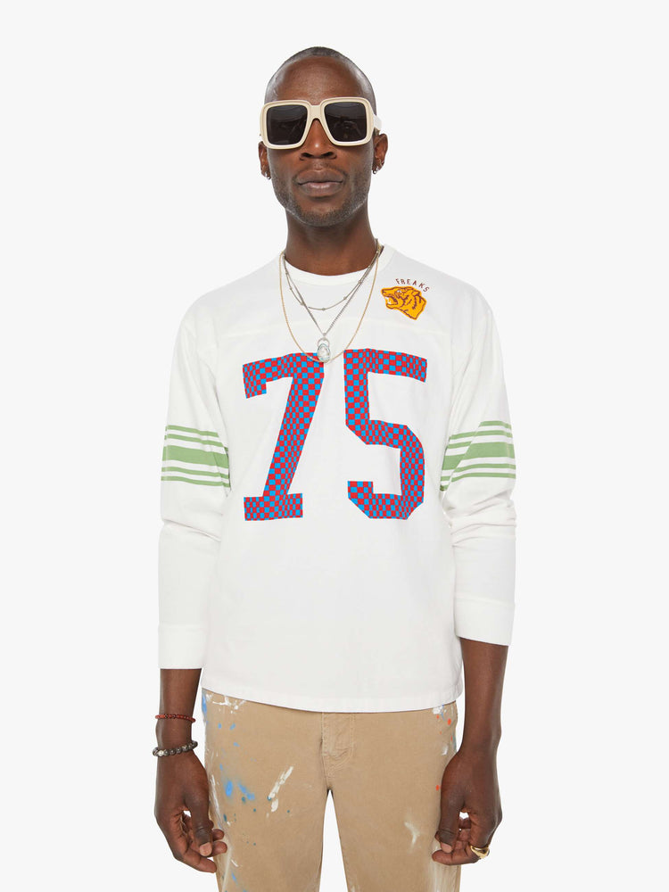 MEN front view view in a white rugby-style tee with a crew neck, long sleeves with a checkered "75" graphic on the front, mint-green stripes on the sleeves and a tiger near the neck.