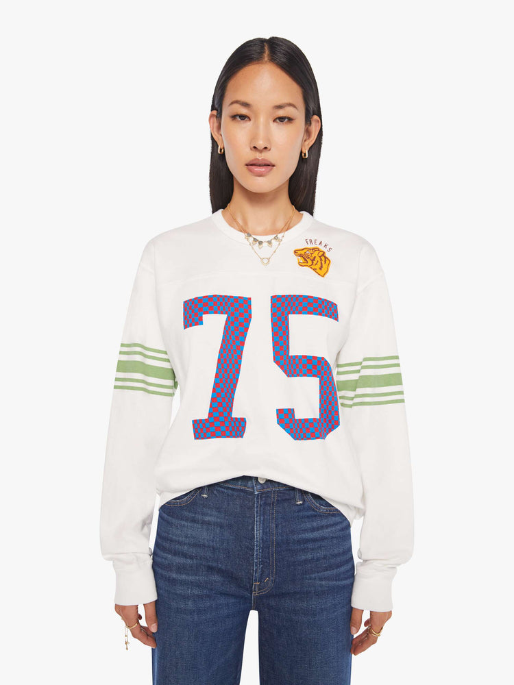 WOMAN front view in a white rugby-style tee with a crew neck, long sleeves with a checkered "75" graphic on the front, mint-green stripes on the sleeves and a tiger near the neck.