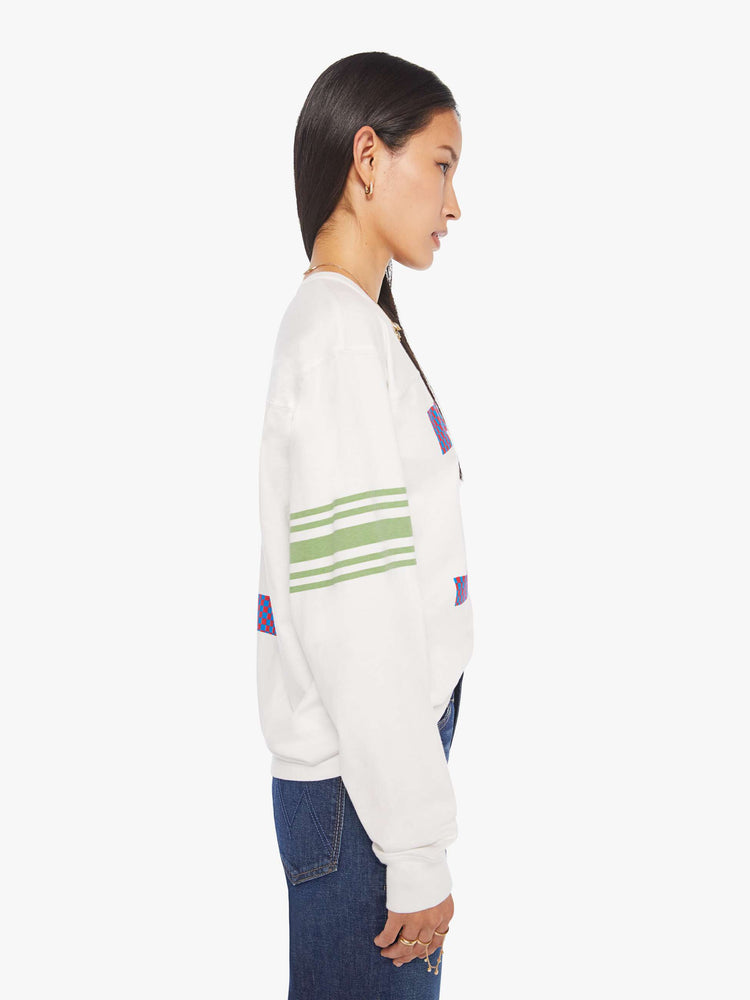 WOMAN side view in a white rugby-style tee with a crew neck, long sleeves with a checkered "75" graphic on the front, mint-green stripes on the sleeves and a tiger near the neck.