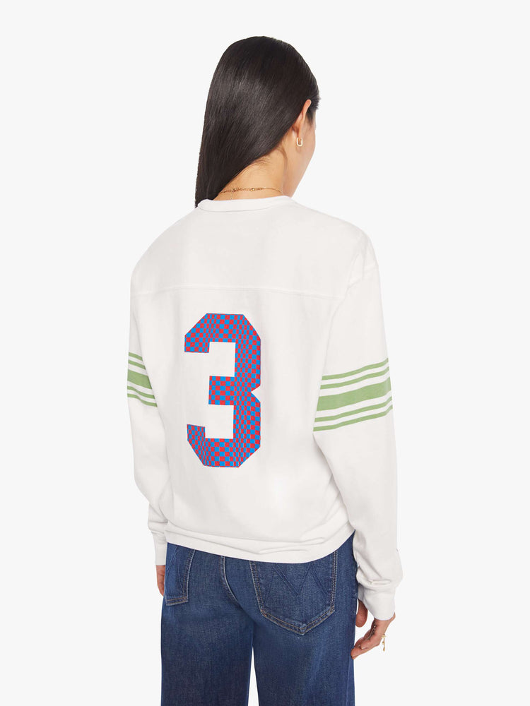 WOMAN back view in a white rugby-style tee with a crew neck, long sleeves with a checkered "75" graphic on the front, mint-green stripes on the sleeves and a tiger near the neck.