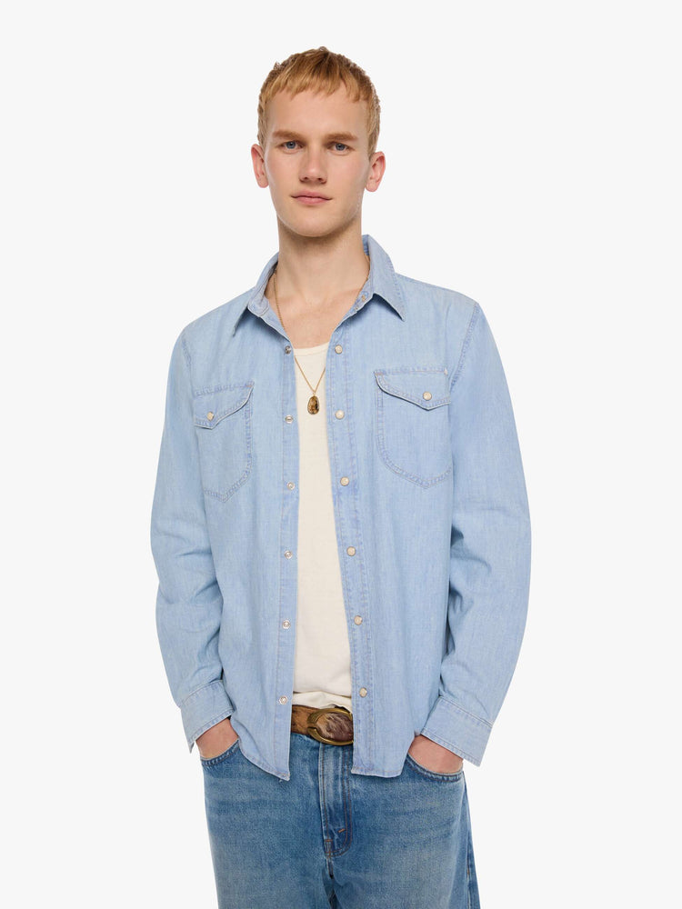 Front view of a man in a light blue   button-up shirt with front patch pockets and a slightly curved hem. 